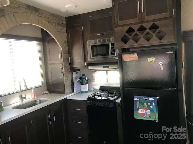 kitchen featuring light countertops, backsplash, a sink, dark brown cabinets, and black appliances