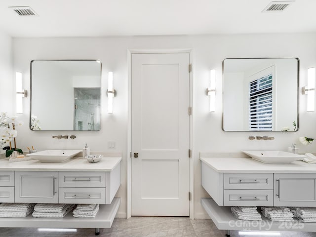 full bath featuring two vanities, visible vents, and a sink