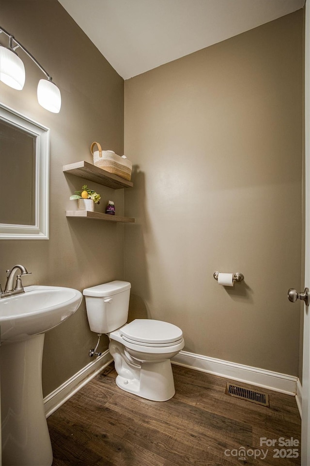 bathroom featuring baseboards, visible vents, toilet, and wood finished floors