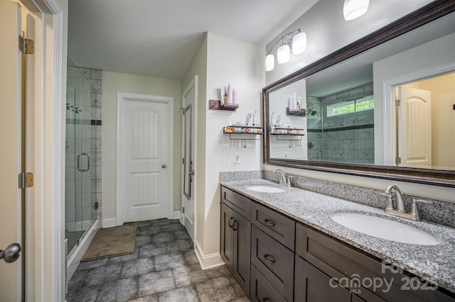 full bathroom featuring stone finish floor, a sink, a shower stall, and baseboards