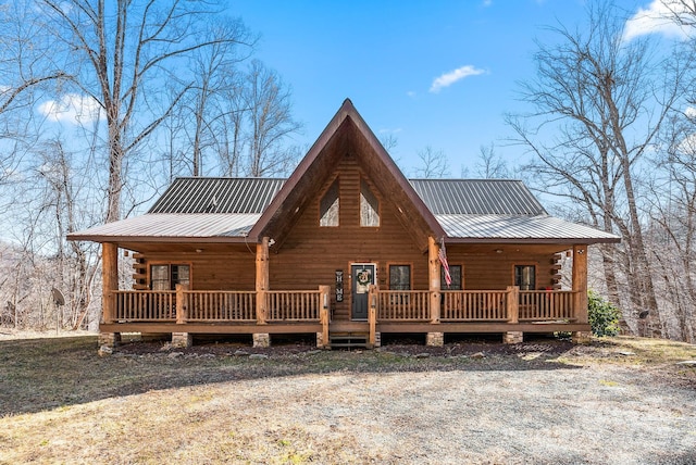 log-style house with covered porch, metal roof, and log exterior