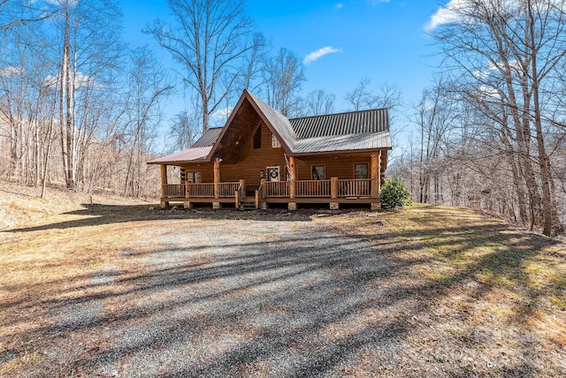 view of front of house featuring gravel driveway, metal roof, and a deck