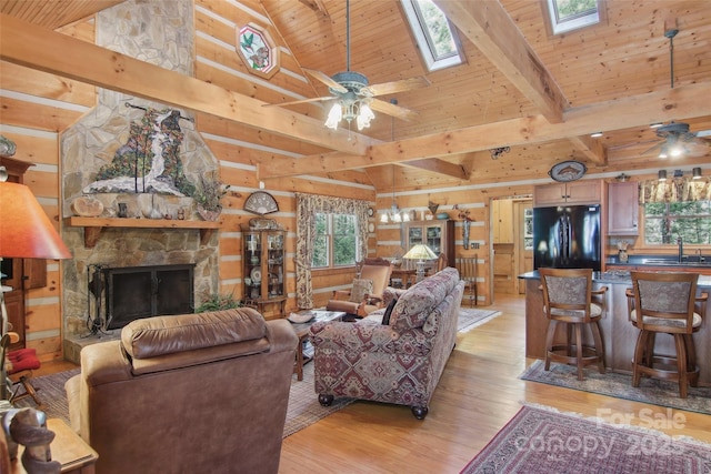 living room with light wood-style floors, wooden ceiling, ceiling fan, and a stone fireplace