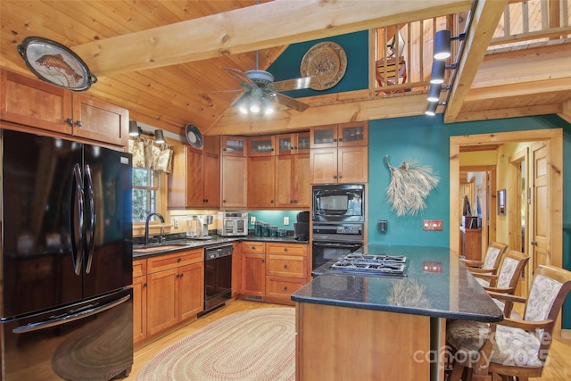 kitchen featuring brown cabinetry, lofted ceiling with beams, glass insert cabinets, black appliances, and a sink