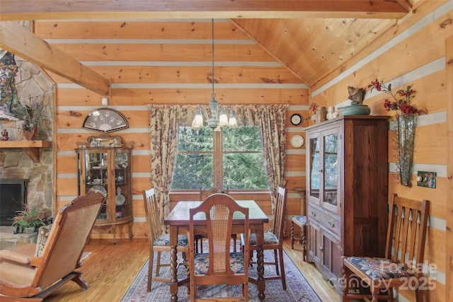 dining area with a fireplace, light wood-style flooring, lofted ceiling with beams, a chandelier, and wooden ceiling