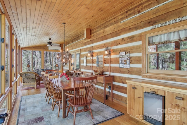 dining area with ceiling fan with notable chandelier, wood walls, wood finished floors, wood ceiling, and vaulted ceiling