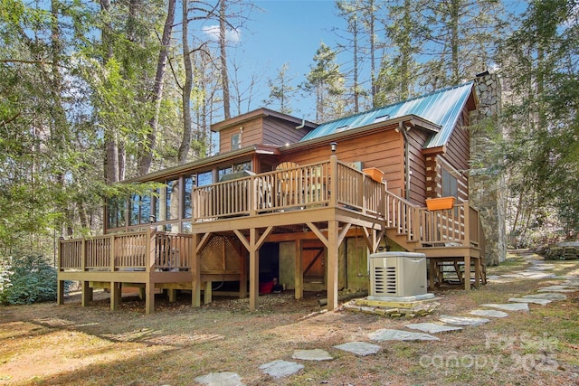 back of property with a deck, metal roof, a chimney, and stairs