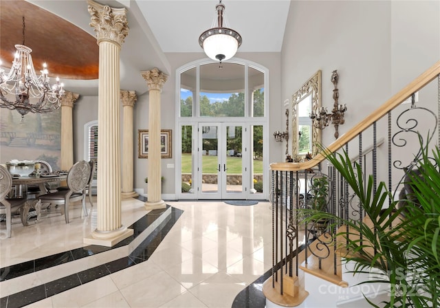 foyer entrance with a chandelier, a towering ceiling, french doors, stairway, and ornate columns