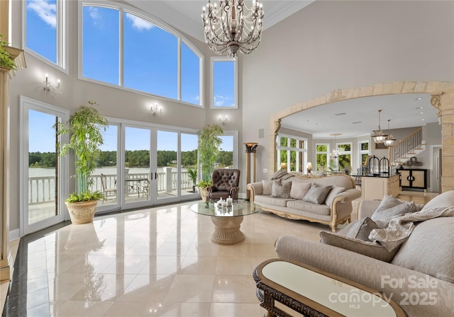 tiled living room with crown molding, a healthy amount of sunlight, and a notable chandelier