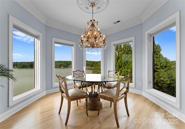 dining room with a healthy amount of sunlight, light wood finished floors, visible vents, and ornamental molding