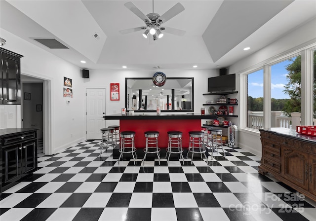 kitchen with a breakfast bar area, visible vents, baseboards, tile patterned floors, and dark countertops