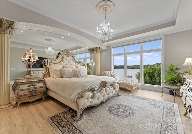 bedroom with ornamental molding, light wood-type flooring, ornate columns, and an inviting chandelier