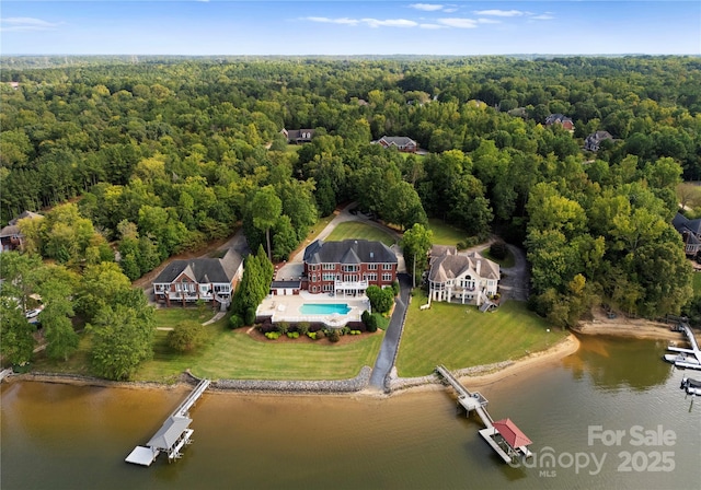 birds eye view of property featuring a water view and a wooded view