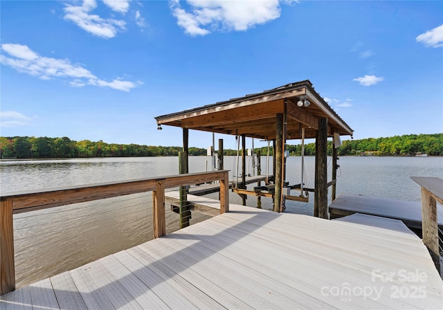 dock area with a water view, boat lift, and a forest view