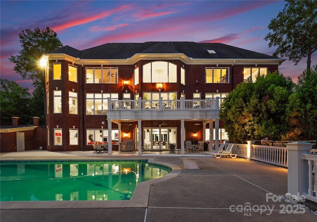 rear view of property featuring a ceiling fan, brick siding, a patio, and a balcony