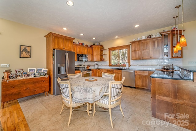 kitchen featuring stainless steel appliances, decorative backsplash, open shelves, brown cabinetry, and pendant lighting