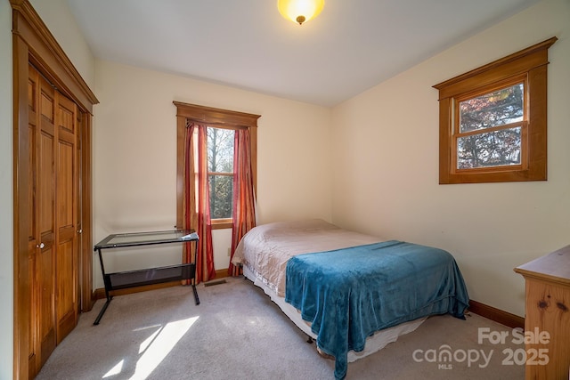 carpeted bedroom featuring baseboards and a closet