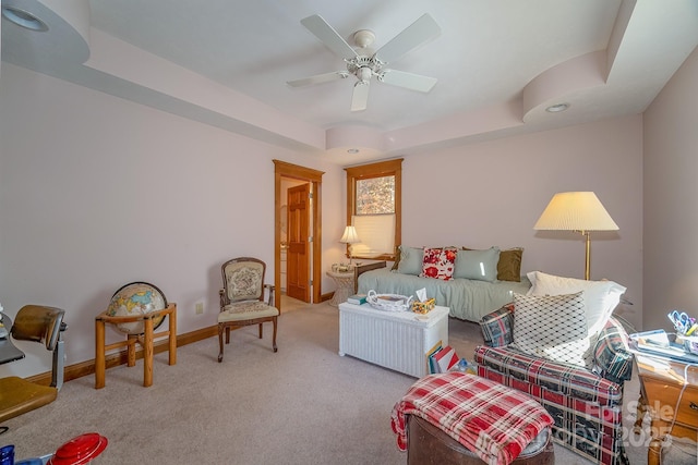 living area with a ceiling fan, a raised ceiling, carpet flooring, and baseboards