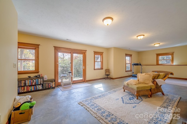 interior space featuring a wealth of natural light, baseboards, and concrete flooring