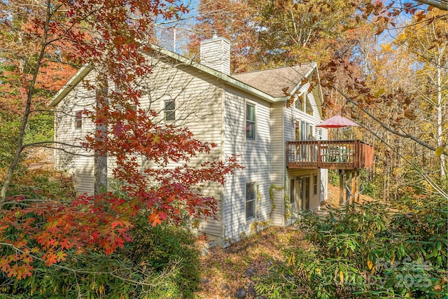 view of side of property with a chimney and a wooden deck