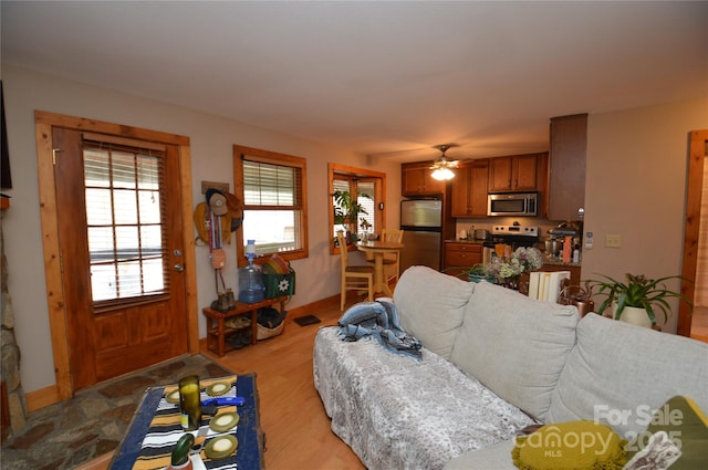 living room featuring light wood finished floors, baseboards, and a ceiling fan