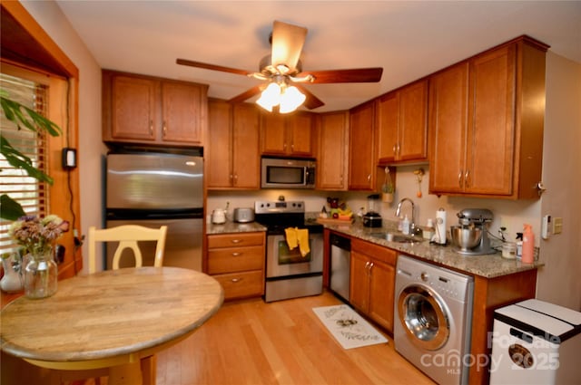 kitchen featuring washer / dryer, brown cabinets, a sink, and appliances with stainless steel finishes