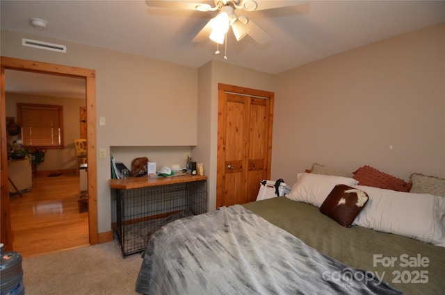 bedroom featuring a closet, visible vents, ceiling fan, and light carpet