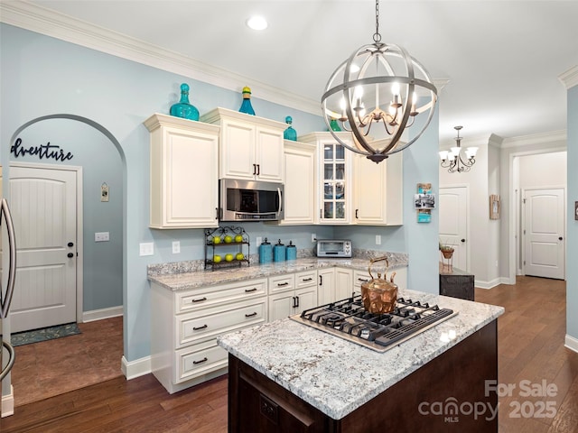 kitchen featuring a notable chandelier, gas stovetop, dark wood-style floors, stainless steel microwave, and glass insert cabinets