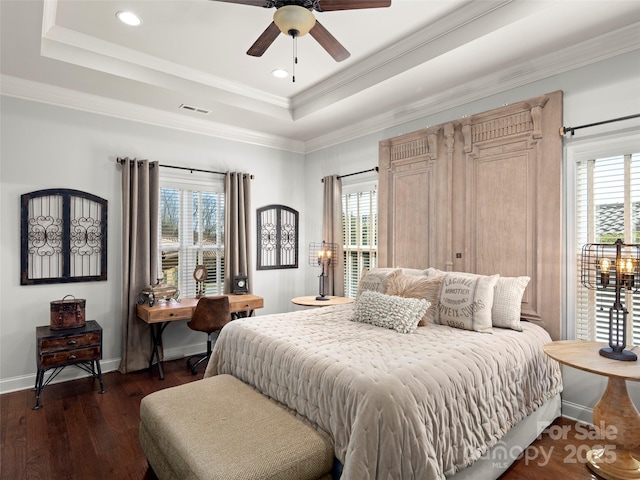 bedroom with a tray ceiling, visible vents, dark wood finished floors, and multiple windows