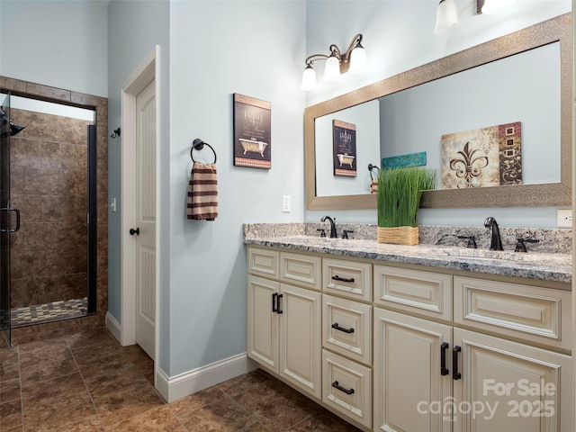 bathroom with a stall shower, a sink, baseboards, and double vanity