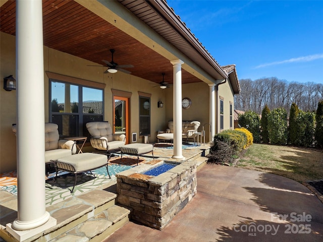 view of patio featuring a ceiling fan and an outdoor living space with a fire pit