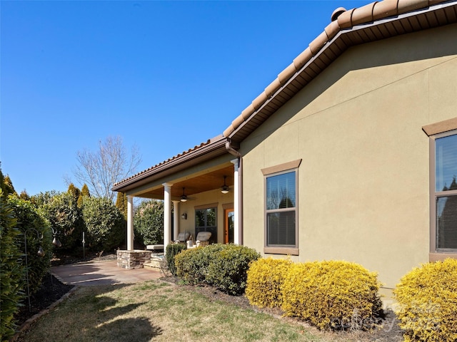 view of home's exterior featuring stucco siding, ceiling fan, a tile roof, and a patio