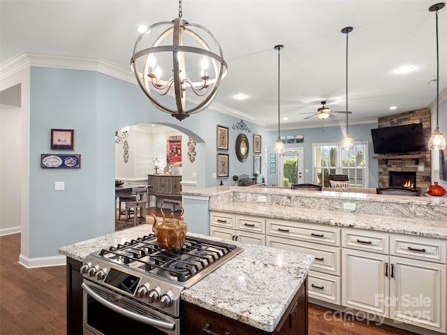 kitchen featuring stainless steel gas range, dark wood finished floors, ornamental molding, and light stone countertops