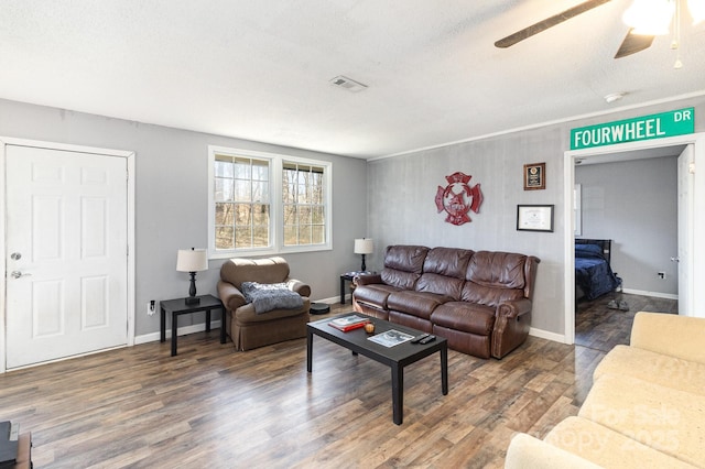 living area featuring visible vents, baseboards, and wood finished floors