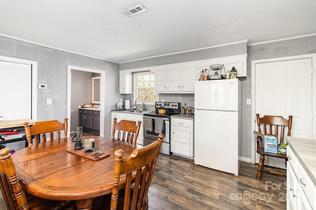 dining room featuring a textured ceiling, dark wood-type flooring, visible vents, and crown molding