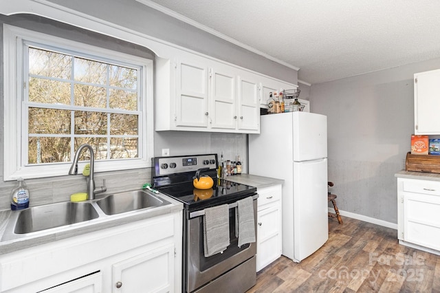 kitchen featuring freestanding refrigerator, electric stove, white cabinetry, and a sink