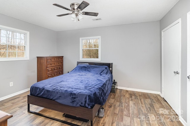 bedroom with wood finished floors, visible vents, and baseboards