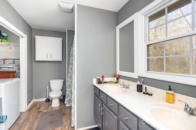 full bathroom featuring double vanity, washer / dryer, a sink, and wood finished floors