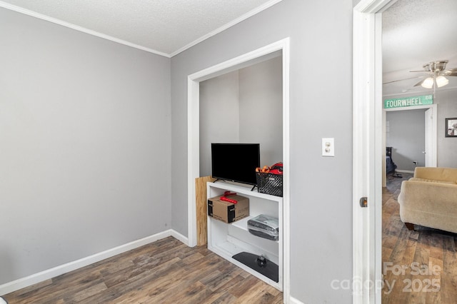 interior space with a textured ceiling, crown molding, wood finished floors, and baseboards