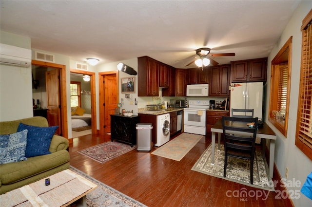 kitchen with dark wood finished floors, visible vents, an AC wall unit, ceiling fan, and white appliances