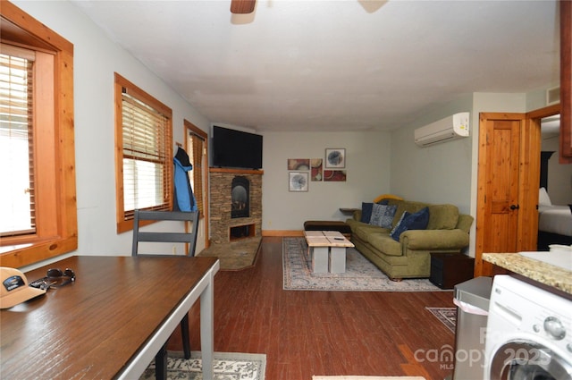 living area featuring ceiling fan, washer / clothes dryer, dark wood-style flooring, a wall mounted air conditioner, and a fireplace