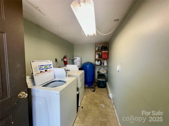 clothes washing area with separate washer and dryer, electric water heater, and baseboards