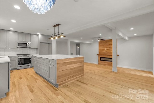 kitchen featuring decorative backsplash, appliances with stainless steel finishes, gray cabinets, light countertops, and light wood-style floors