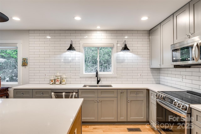 kitchen featuring stainless steel appliances, gray cabinets, light countertops, visible vents, and a sink