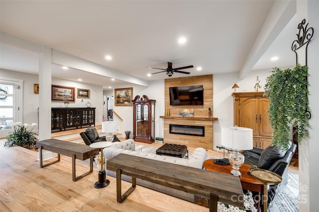 living area with a ceiling fan, light wood-type flooring, a fireplace, and recessed lighting