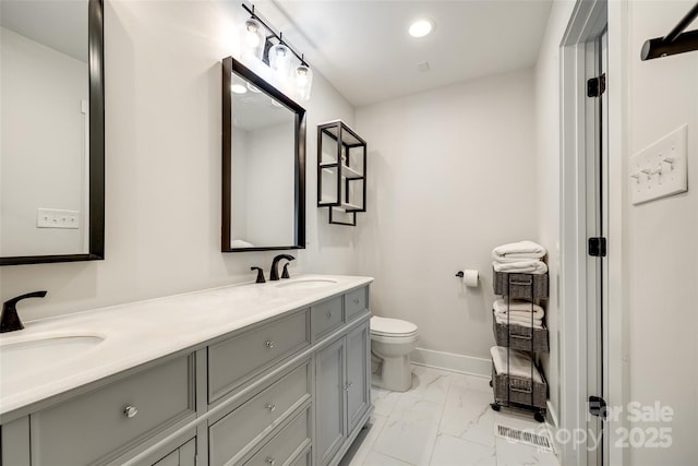 full bathroom with marble finish floor, double vanity, toilet, a sink, and baseboards