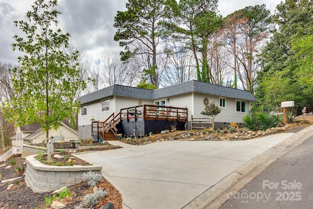 view of front of property with a deck, mansard roof, crawl space, and a shingled roof