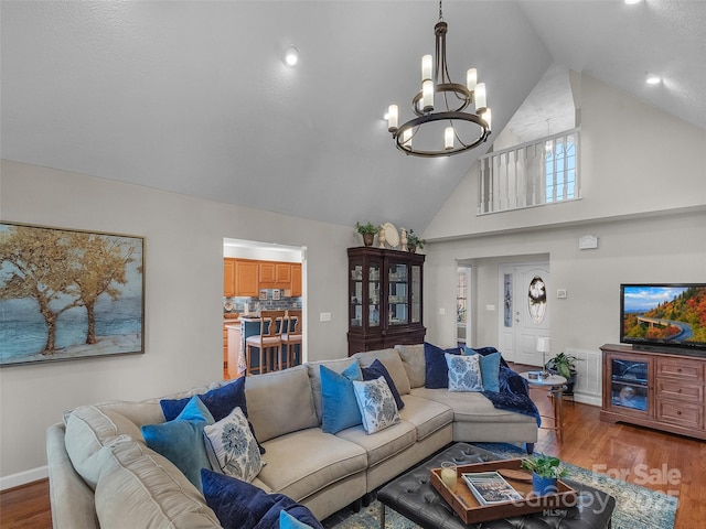 living room with high vaulted ceiling, a notable chandelier, baseboards, and wood finished floors