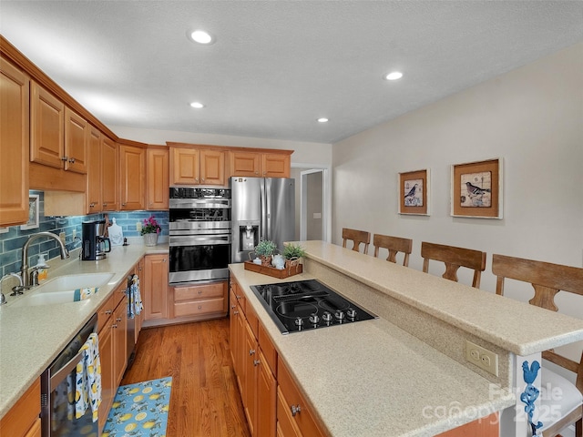 kitchen featuring stainless steel appliances, a breakfast bar, a kitchen island, and a sink