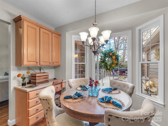 dining room with a notable chandelier, baseboards, and wood finished floors